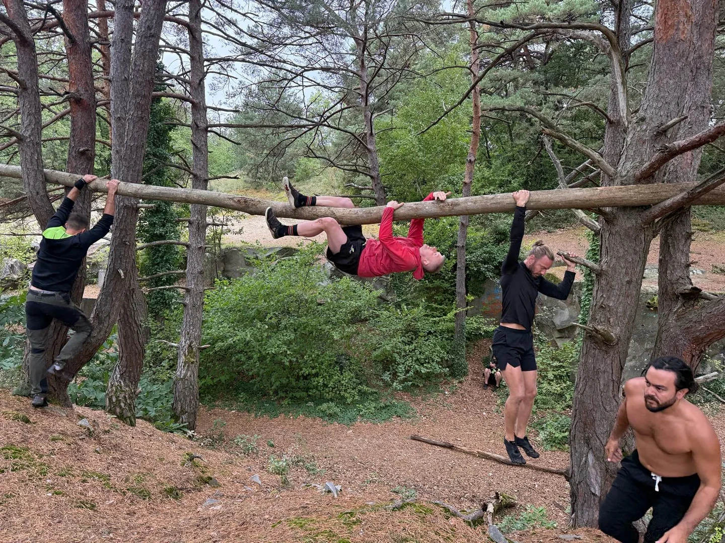 MovNat participants practicing climbing on a fallen branch outdoors